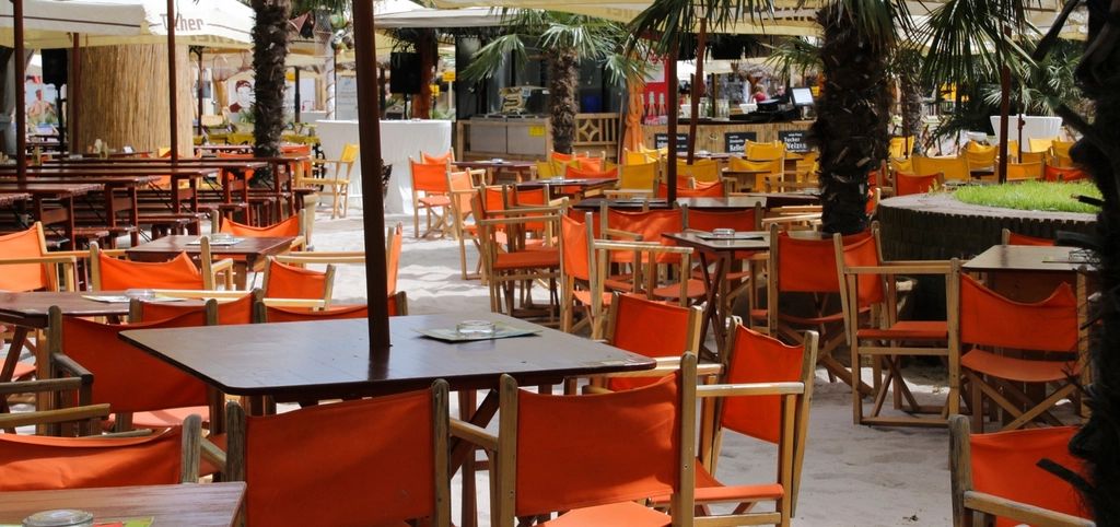 La terrasse du cabanon sous les palmiers, chaises orange face à la mer